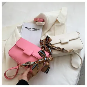 Detail of pink and beige shoulder bags with printed silk scarves and leather straps