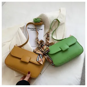 Detail of candy-colored crossbody bags with floral scarf handles on white blazer