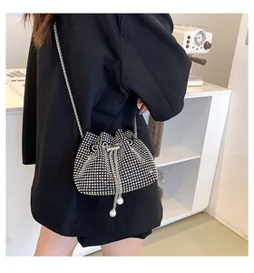 Detail of black rhinestone bucket bag featuring a chain strap and pearl drawstring accents