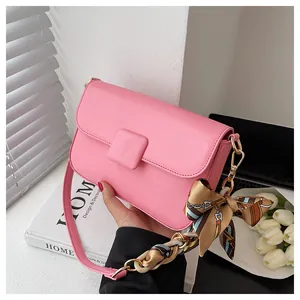 Detail of pink shoulder bag with matte leather finish and decorative silk scarf chain strap