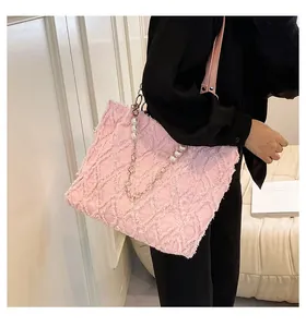 Détail du cabas en denim rose avec texture effilochée, perles et bandoulière chaîne
