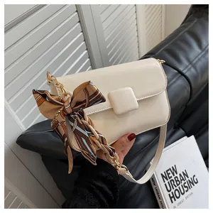 Detail of cream leather shoulder bag with decorative silk scarf and square buckle clasp