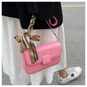 Pink crossbody bag with decorative striped silk scarf handle and matte leather finish