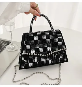 Dettaglio borsa nera da donna con motivo a scacchi in strass e tracolla a catena in metallo