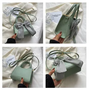 Detailed views of light green faux leather small square bag with large grey bow decoration