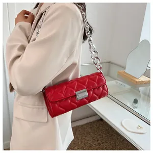 Détail du sac rouge matelassé à motif de cœur avec bandoulière chaîne argentée porté