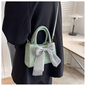 Fashionable mint green small square bag with large sheer bow on a female model