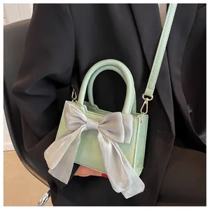 Detail of mint green handbag with a large silver bow decoration shown on a model