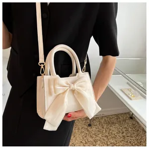 Detail of off-white crossbody bag with oversized mesh bow and gold hardware accents