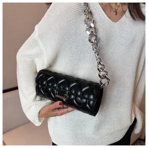 Détail du sac en cuir noir matelassé en cœur avec chaîne argentée et fermoir métallique