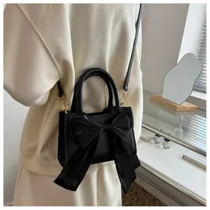 Close-up of elegant black handbag with a large decorative bow and polished top handle
