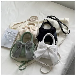 Flat lay of small crossbody square bags with large fabric bows in four elegant colors