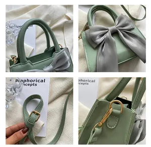 Close-up of sage green mini handbag featuring a grey silk bow and gold hardware details