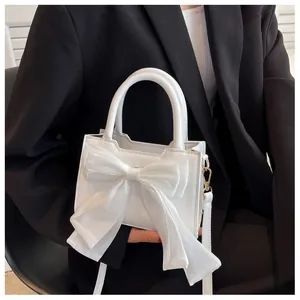 Close-up of a white fashion handbag featuring a decorative large tulle bow and gold hardware
