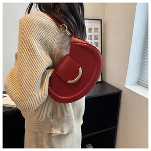 Detail der roten Satteltasche aus Leder mit goldener Schnalle auf Strick-Outfit