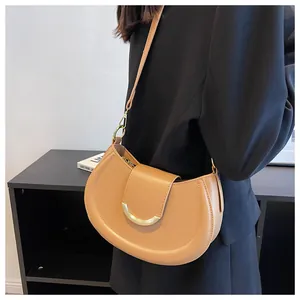 Detail einer braunen Satteltasche aus PU-Leder mit goldener Schnalle an einem Model