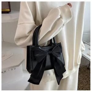 Detail of black small square handbag featuring a large sheer fabric bow decoration
