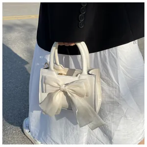 Close-up of white small handbag with a large tulle bow decoration and gold hardware accents