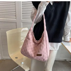 Detail of pink quilted shoulder bag with brand tag and trendy checkerboard texture