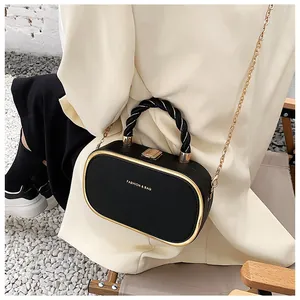 Detail van de zwarte box-tas met textuur, gouden randen en elegante kettingriem