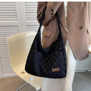 Close-up of black checkered texture shoulder bag with brown leather brand label detail