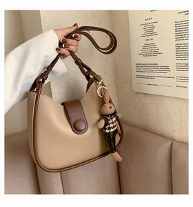 Detail van een chique beige en bruine leren schoudertas met een schattige konijn-hanger