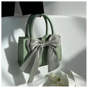 Macro detail of avocado green leather square bag with large sheer organza bow accent