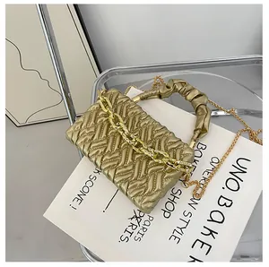 Detail of champagne gold quilted handbag with V-weave texture and chunky metal chain link