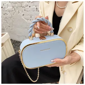 Detail van lichtblauwe box bag met gouden metalen rand en stijlvol spiraalhandvat