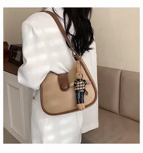 Detail van een chique beige en bruine emmertas met een schattige konijnenhanger en magneetflap