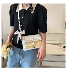 Dettaglio borsa a tracolla in pelle bianca con inserti intrecciati e foulard in seta