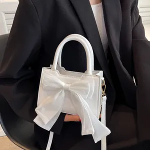White mini handbag with oversized bow detail, top handle and crossbody strap for women