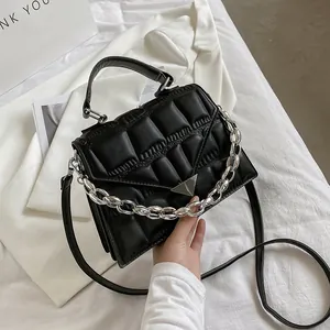 Detail of black quilted leather shoulder bag with bold silver metal chain and top handle