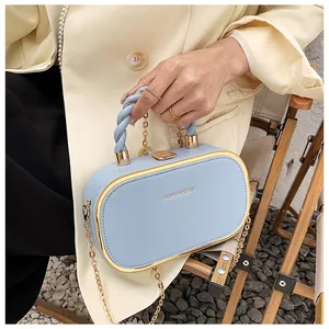 Detail van lichtblauwe crossbody tas met gouden rand en geweven handvat