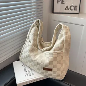 Chic beige checkered hobo bag on white books with minimalist soft lighting design