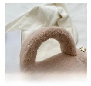 Gros plan du sac à main rose en fausse fourrure avec poignée épaisse et anneaux dorés