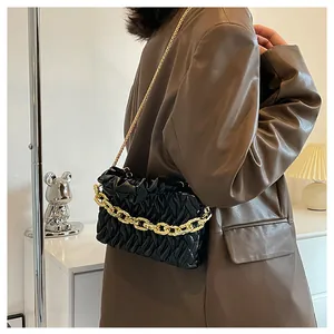 Detail of black pleated shoulder bag with gold chunky chain handle and metal strap