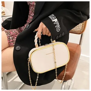 Detail van beige lederen box bag met gouden metalen frame en gevlochten handvat