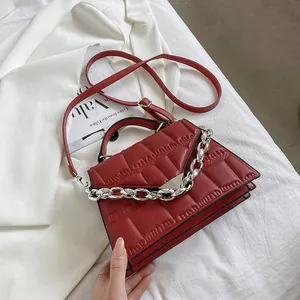 Close-up of deep red quilted leather handbag with silver chain strap and metal buckle