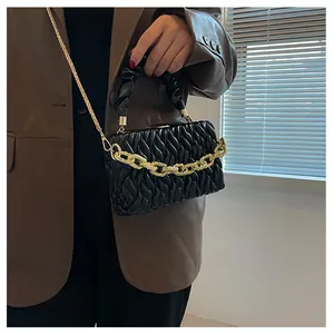Chic black matelasse handbag with chunky gold chain detail worn by a model