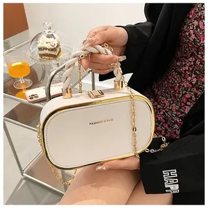 Detail van de crème crossbodytas met een geweven handvat en gouden metalen rand