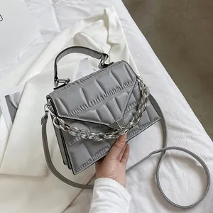 Detail of grey quilted handbag featuring silver chunky chain and triangle metal buckle