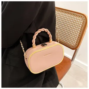 Modieuze roze box-tas met gouden frame en gedraaid handvat gedragen door model