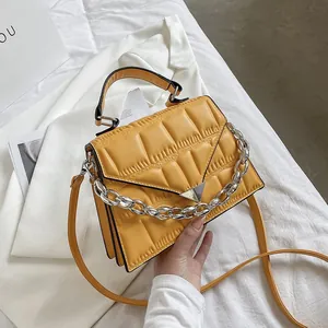 Close-up of yellow pleated crossbody bag with silver chain and metal triangle detail