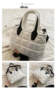 Detail of white quilted down tote bag with black leather handles and shiny fabric texture