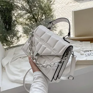 Detail of white crocodile texture faux leather handbag with silver chain and metal clasp
