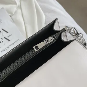 Macro detail of black and white contrast handbag featuring silver zipper and leather texture