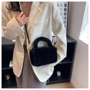 Détail d'un sac à main en fausse fourrure noire porté avec un blazer blanc élégant