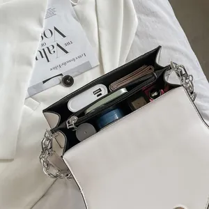 Detailed view of white flap crossbody bag with silver chain strap and multiple compartments