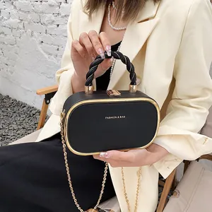 Elegante zwarte ovale clutch met gouden details en kettingriem gedragen door model